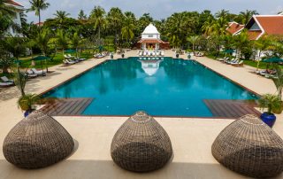 Swimming Pool surrounded with loungers and palm trees